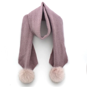 Detailed texture of dusty pink ribbed knit scarf with fluffy faux fur pom-poms on ends