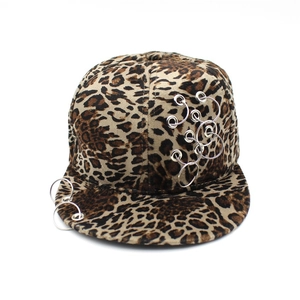 Detalle de gorra de béisbol con estampado de leopardo, anillos metálicos y textura de terciopelo