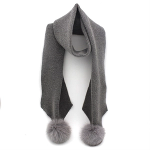Detail view of dark grey ribbed knit scarf featuring fluffy fox fur pom-poms on both ends
