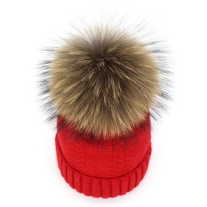 Detailed top view of red knitted beanie featuring a large 15cm brown faux fur pompom