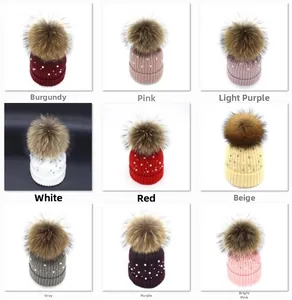 Close-up of pearl-embellished knitted hats with faux fur pom-poms in nine vibrant colors
