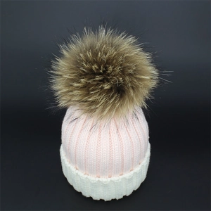 Pink and white knit beanie with a fluffy brown raccoon fur pompom for winter warmth