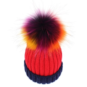 Winter knitted beanie for women featuring a large colorful pompom and navy folded brim