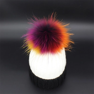 Detail of winter knitted beanie with cream white body and large colorful gradient pompom