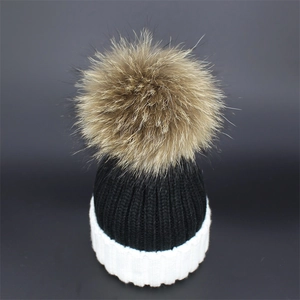 Close-up of black and white knit beanie featuring a large fluffy pom-pom and thick cuff