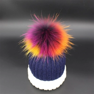Detail shot of winter knit beanie showing vibrant multi-color faux fur pompom and textures