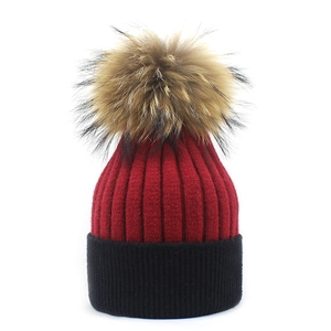 Detail of red and black knitted cashmere hat with a large fluffy pom-pom decoration