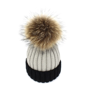Close-up of dual-tone knit beanie featuring gray and black contrast with a fluffy fur pom-pom