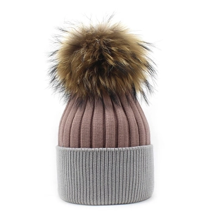 Detail of two-tone knit beanie with pink and grey ribs and a fluffy pom-pom