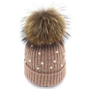 Detailed knit texture of pink winter hat with white pearls and a fluffy pom-pom