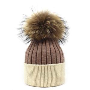 Close-up of ribbed knit texture on coffee and beige wool beanie with fluffy pom pom