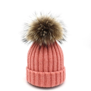 Orange pink ribbed wool knit beanie for women with a large brown faux fur pom-pom topper