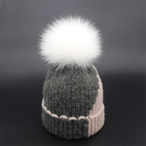 Knit winter beanie with white fur pom pom and pink grey patchwork rib texture