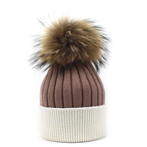 Detail of two-tone cashmere knit beanie with large fluffy faux fur pompom and cuff