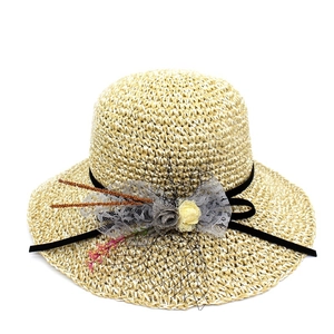 Détail d'un chapeau de paille beige avec fleurs en dentelle grise et voile en résille