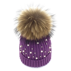 Detail view of purple ribbed knit beanie with white pearls and large faux fur pompom