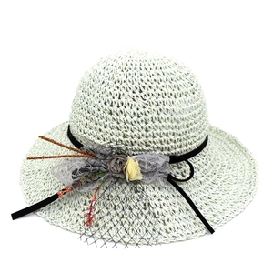 Détail d'un chapeau de paille tissé avec dentelle grise, fleur en résille et ruban noir