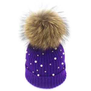 Detailed texture of purple knit beanie with white pearls and fluffy raccoon fur pompom