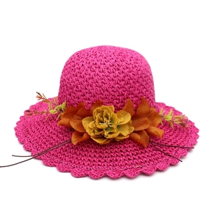 Detailed macro view of vibrant rose red straw sun hat with orange floral accent