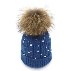 Detailed close-up of navy knit beanie with elegant white pearls and silver metal beads