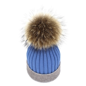 Blue and grey cashmere knit hat with a large fluffy raccoon fur pompom for winter