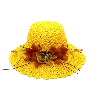 Women's yellow straw sun hat featuring decorative floral accents and a wavy beach brim