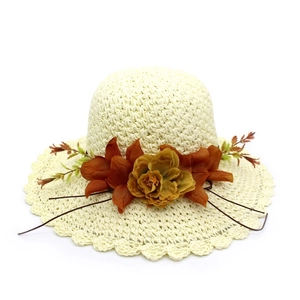Detailed view of handwoven straw sun hat with decorative fabric flowers and wavy brim