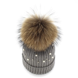 Close-up of grey ribbed knit beanie with white pearls and large fluffy fur pompom