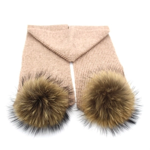 Detailansicht des camel farbenen Strickschals mit zwei flauschigen gemischten Bommeln