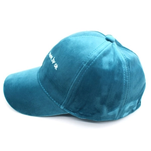 Close-up of side embroidery love by ok text on teal velvet texture baseball cap