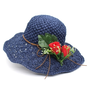 Detail of navy blue raffia hat with wide brim, straw hollow weave and red rose floral trim