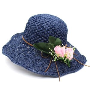 Detail of navy straw sun hat featuring pink floral decor and faux leather cord