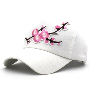 Detailed close-up of pink cherry blossom embroidery on a white cotton baseball cap