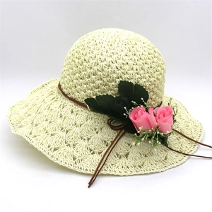 Detail of wide brim raffia hat with decorative pink roses and green leaf trim for women