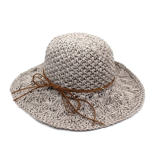 Detailed close-up of tight raffia crochet texture and thin brown leather bow on sun hat