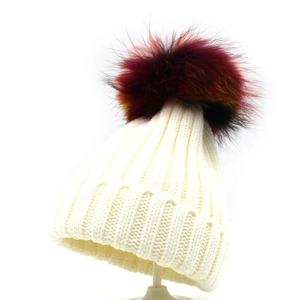 Detailed close-up of white ribbed knit beanie featuring a colorful raccoon fur pom-pom