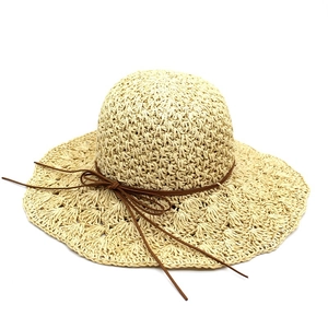 Macro detail of hand-knitted beige raffia sun hat with brown drawstring and bow detail