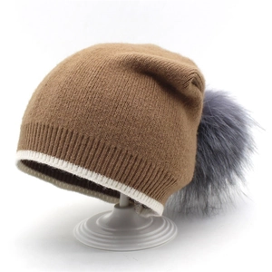 Détail du bonnet en maille marron avec pompon en fausse fourrure grise et doublure polaire