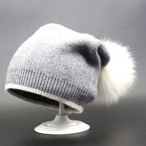 Gray knitted beanie featuring a white fox fur pompom and contrast brim detailing