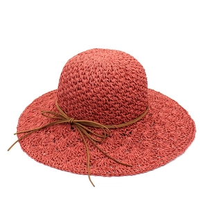 Detail of hand-woven raffia sun hat with elegant wavy brim and thin brown leather bow ribbon
