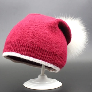 Deep pink knitted beanie with white stripe brim and large white faux fur pompom