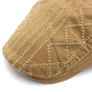 Macro shot of cross-stitch embroidery and textured cotton fabric on a vintage flat cap