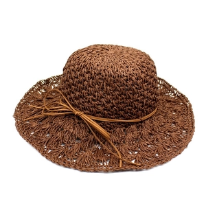 Detailed macro view of brown raffia sun hat showing intricate woven texture and suede bow