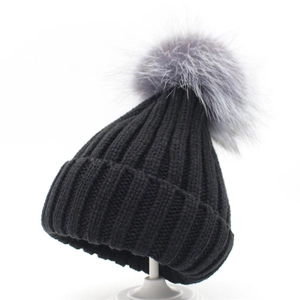Detail of thick ribbed knit winter beanie in black with a large grey faux fur pom pom