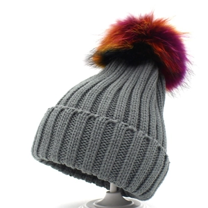 Detailed texture of grey rib-knit winter beanie with a colorful faux fur pom-pom topper