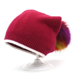 Dettaglio del berretto in maglia rosa con trama fine e pompon in finta pelliccia colorata