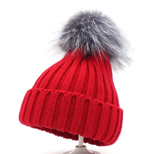 Winter red knitted beanie with a fluffy grey faux fur pom pom on a white stand