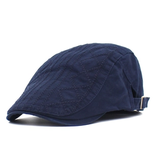 Detail of dark blue cotton flat cap featuring diamond quilted embroidery and metal buckle