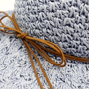 Close-up of light blue hand-woven raffia sun hat with brown bow tie details
