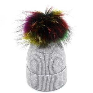 Bonnet en tricot gris clair pour femme avec un grand pompon coloré pour la chaleur d'hiver